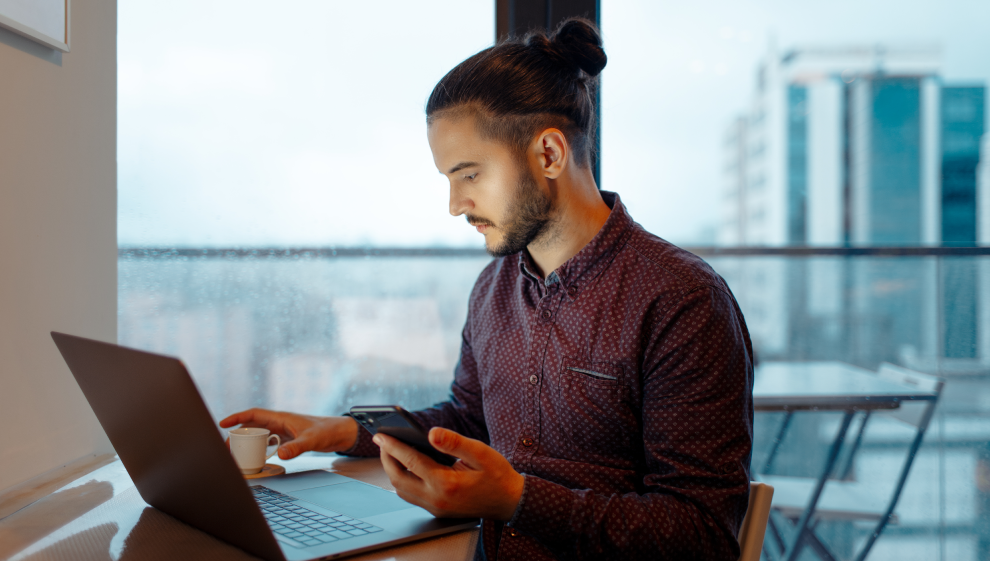 A man using his laptop and smartphone to work